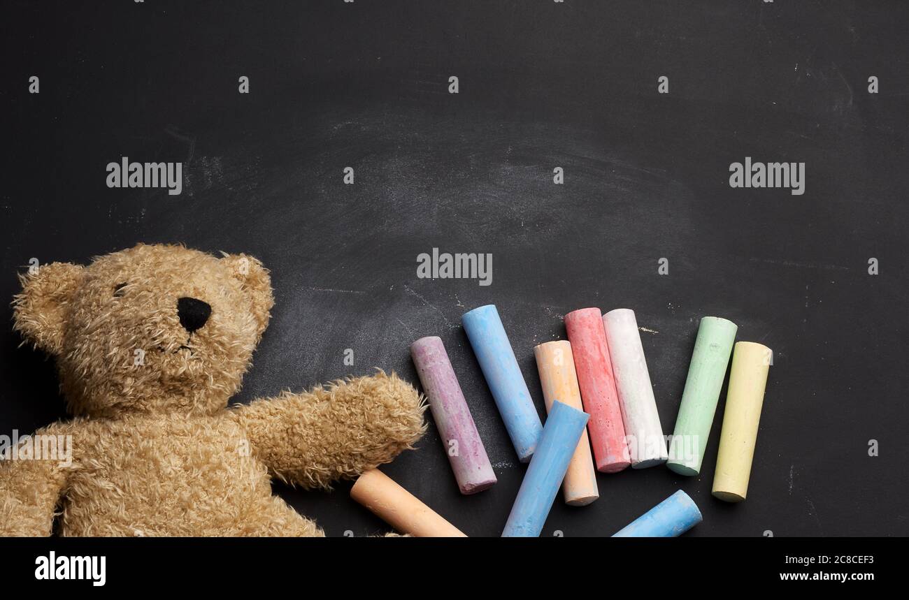 ours en peluche brun et crayons colorés sur tableau noir, de retour à l'école Banque D'Images