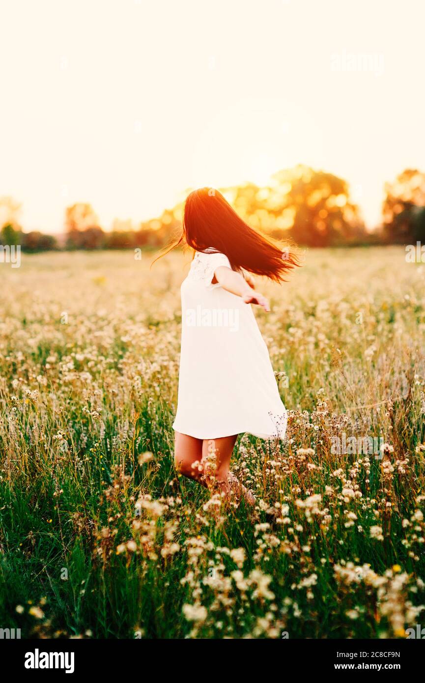 Belle jeune femme sensuelle tendre dansant dans une prairie le champ de fleurs au coucher du soleil en Sunbeam Healthy Lifestyle, Freedom concept Banque D'Images