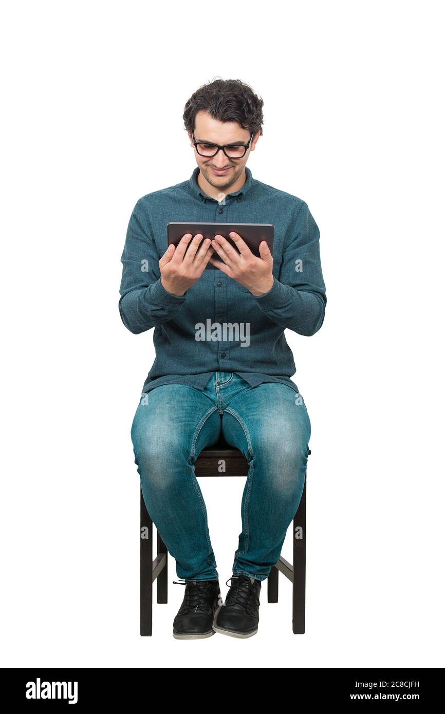 Jeune élève de sexe masculin, assis sur une chaise, utilisant une tablette pour PC pour se divertir. Concept moderne d'éducation, travailler et étudier à partir de la maison. Heureux m Banque D'Images