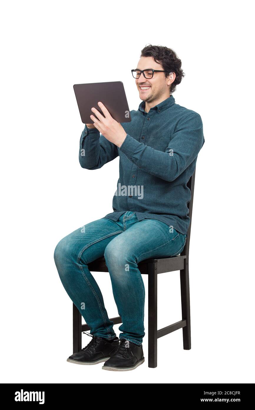 Jeune élève de sexe masculin, assis sur une chaise, utilisant une tablette pour PC pour se divertir. Concept moderne d'éducation, travailler et étudier à partir de la maison. Heureux m Banque D'Images
