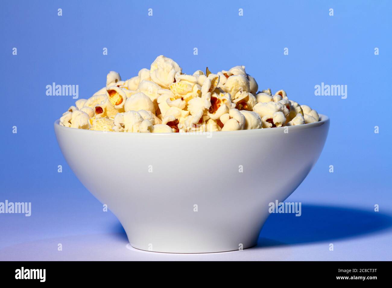 Bol de pop-corn frais isolé sur fond bleu Banque D'Images