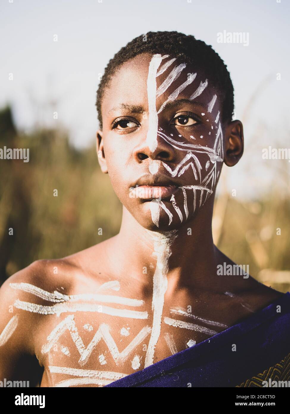 portrait d'un garçon africain avec une peinture ethnique du visage et un habillage dans la brousse Banque D'Images