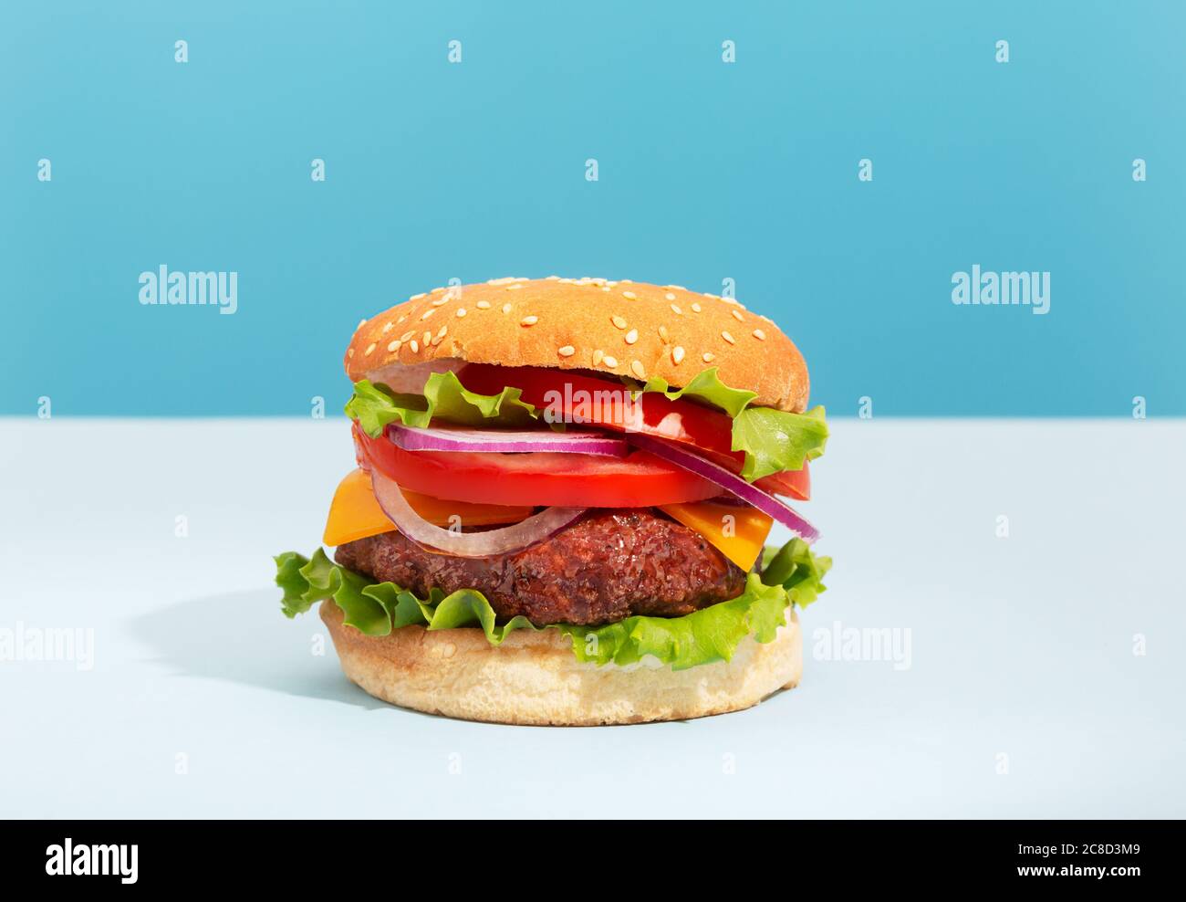 Hamburger de bœuf frais et juteux avec frites placées sur du bleu arrière-plan créatif et tendance Banque D'Images