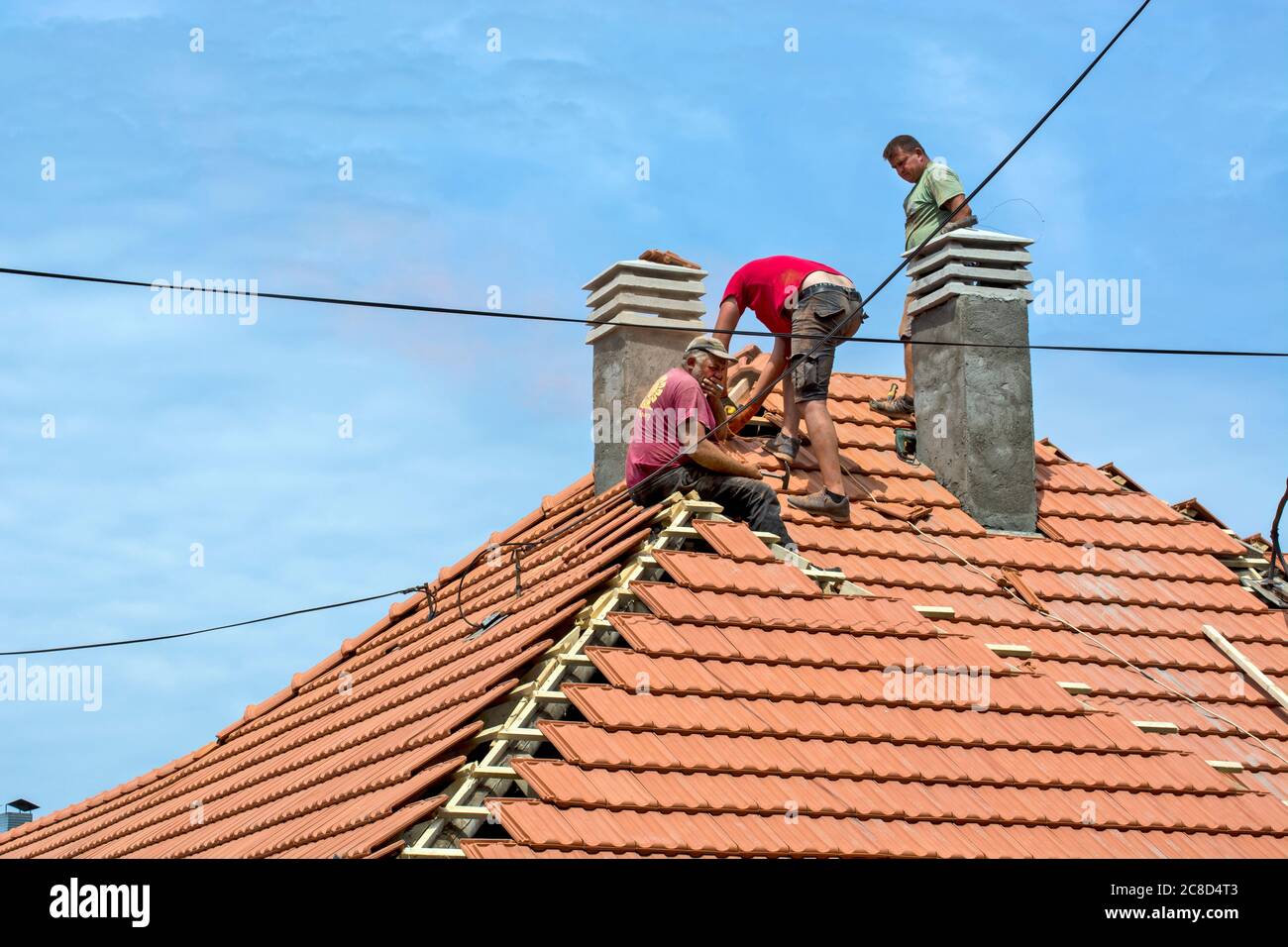 Zrenjanin, Serbie, 23 juillet 2020. Un groupe de maîtres travaille sur le toit d'une maison privée pour remplacer un vieux carrelage. Ils ont une belle journée et stable Banque D'Images