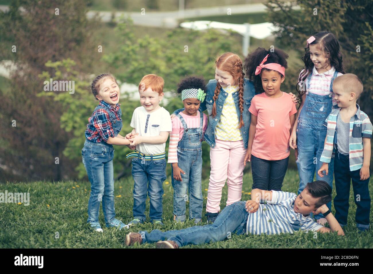 Enfants de cultures différentes ensemble. Dans le parc sur herbe verte en pleine longueur. Le concept des peuples, de l'amitié, de l'enfance et de la coopération interculturelle Banque D'Images
