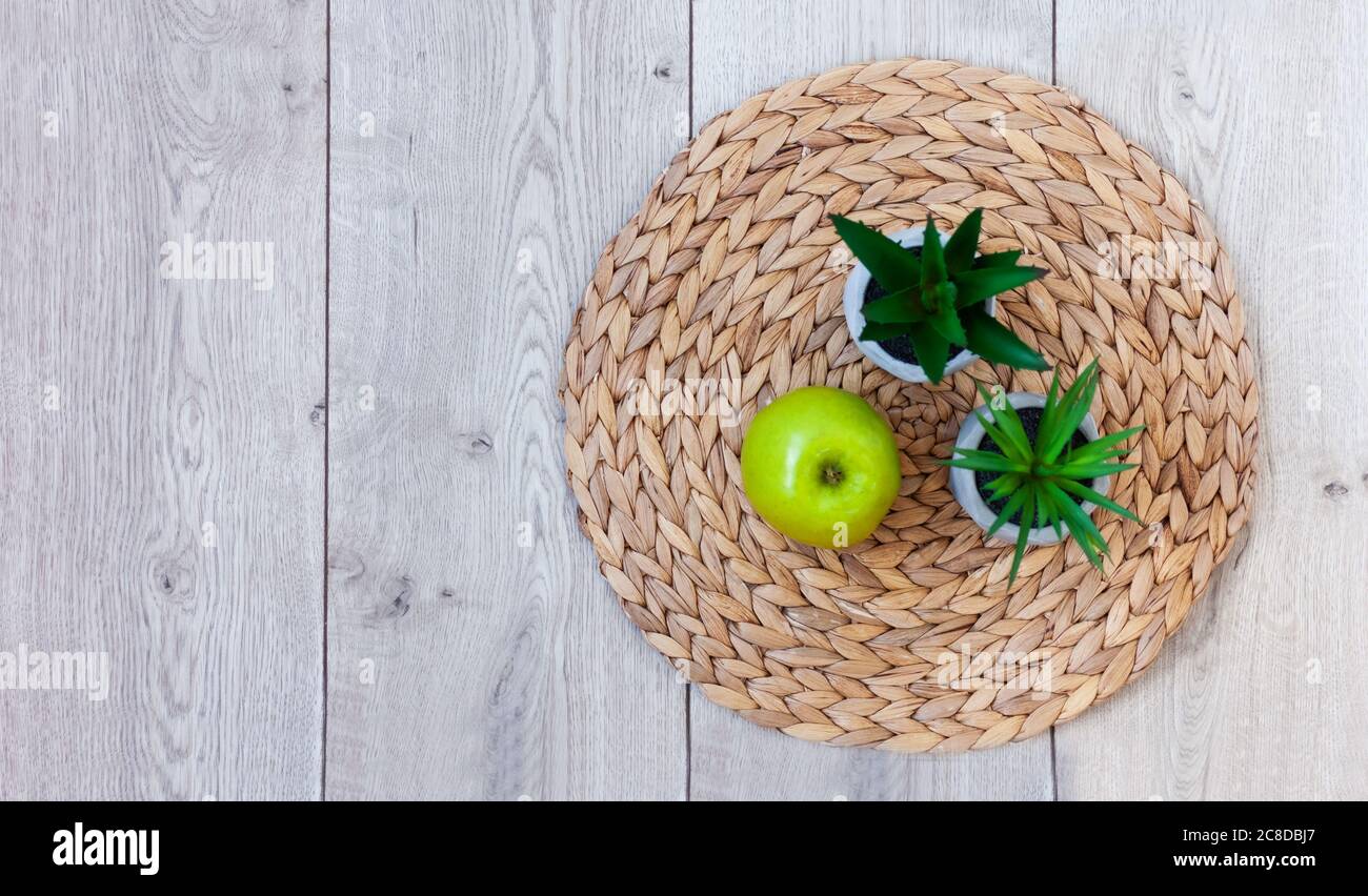 Décoration intérieure chaleureuse : pomme verte et plantes en pots sur un support en osier sur une table en bois. Quarantaine concept de rester à la maison Banque D'Images