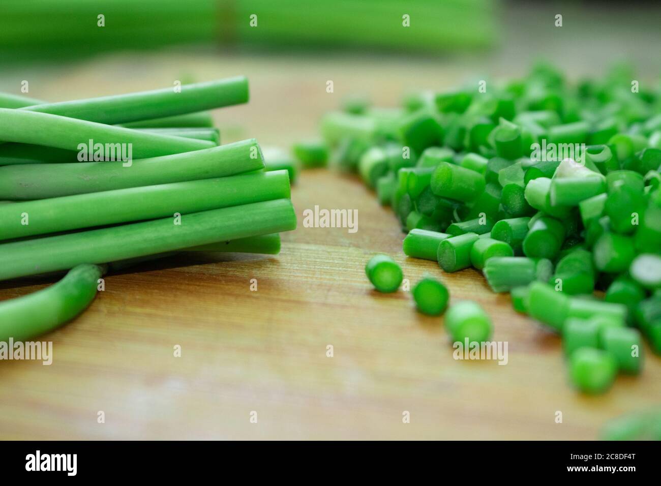 Couper l'ail vert sur une planche à découper en bois Banque D'Images