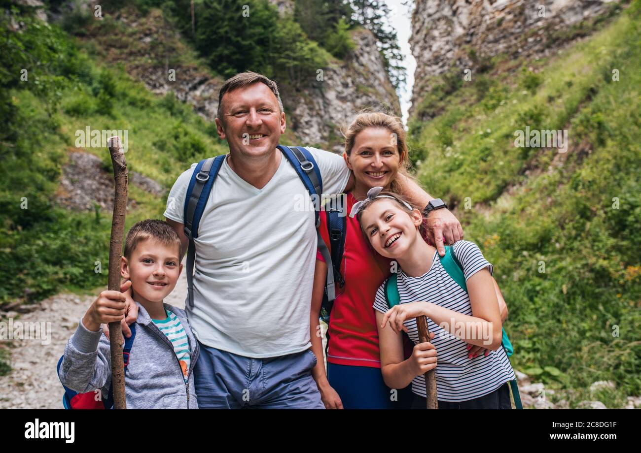Portrait de parents souriants et de leurs deux petits enfants sur un sentier accidenté lors d'une randonnée en famille Banque D'Images