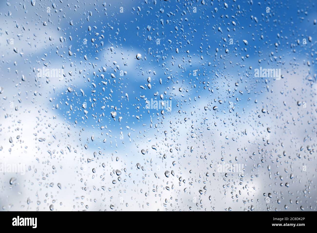 Gouttes de pluie sur la vitre sur fond flou du ciel avec des nuages. De belles gouttes d'eau, temps pluvieux Banque D'Images