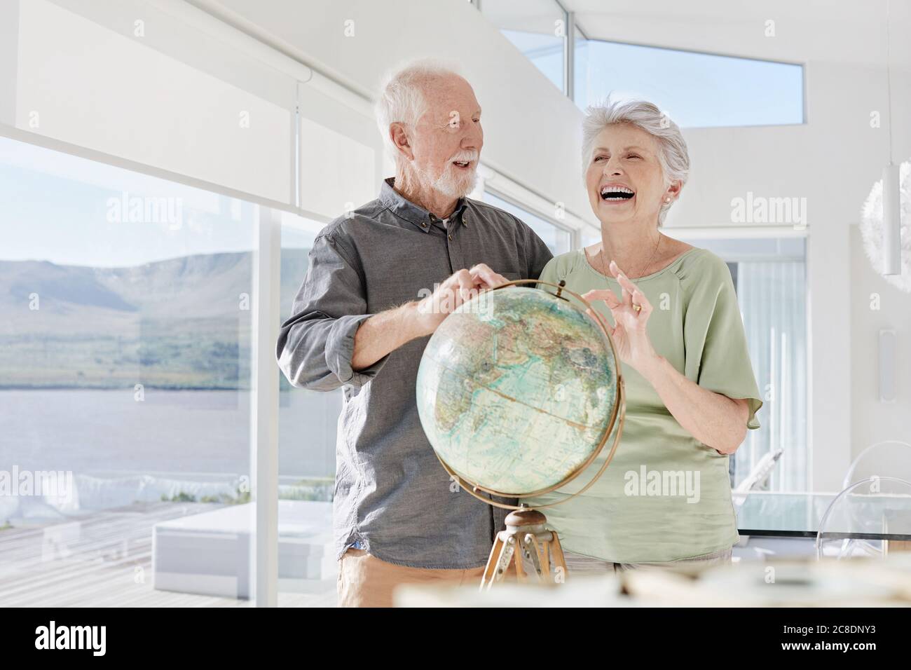 Couple senior heureux avec globe dans une villa de luxe Banque D'Images