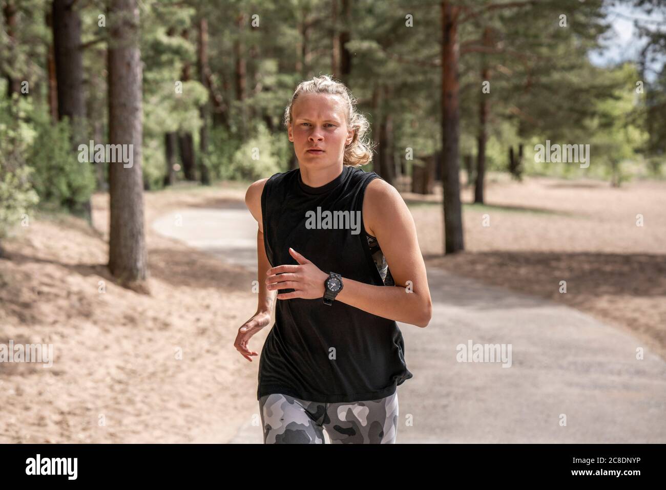 Jeune femme blonde jogging dans les bois Banque D'Images