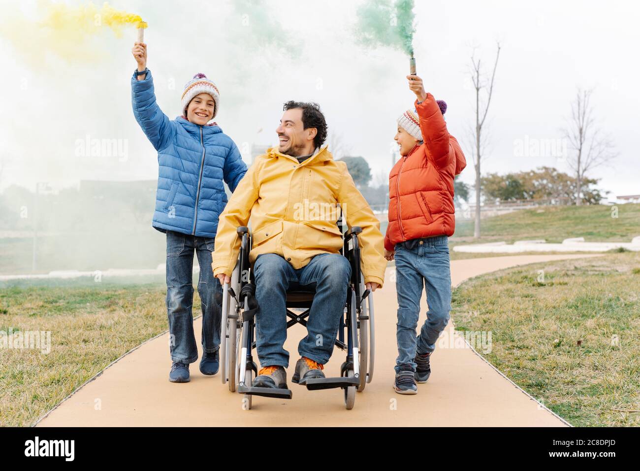 Homme en fauteuil roulant pendant que les garçons marchent avec la détresse tordue sentier dans le parc Banque D'Images