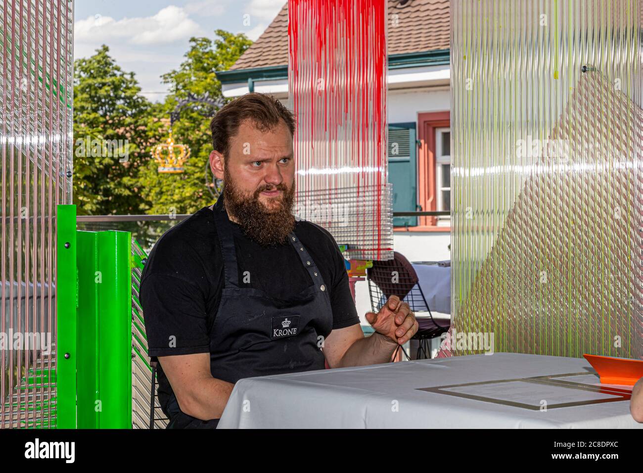Restauration extérieure avec cloisons artistiquement conçues et serveurs avec masques de protection à l'Hôtel Krone à Weil am Rhein, Allemagne Banque D'Images