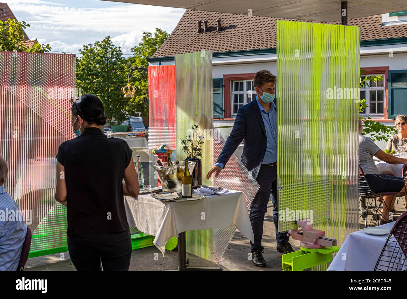 Restauration extérieure avec cloisons artistiquement conçues et serveurs avec masques de protection à l'Hôtel Krone à Weil am Rhein, Allemagne Banque D'Images