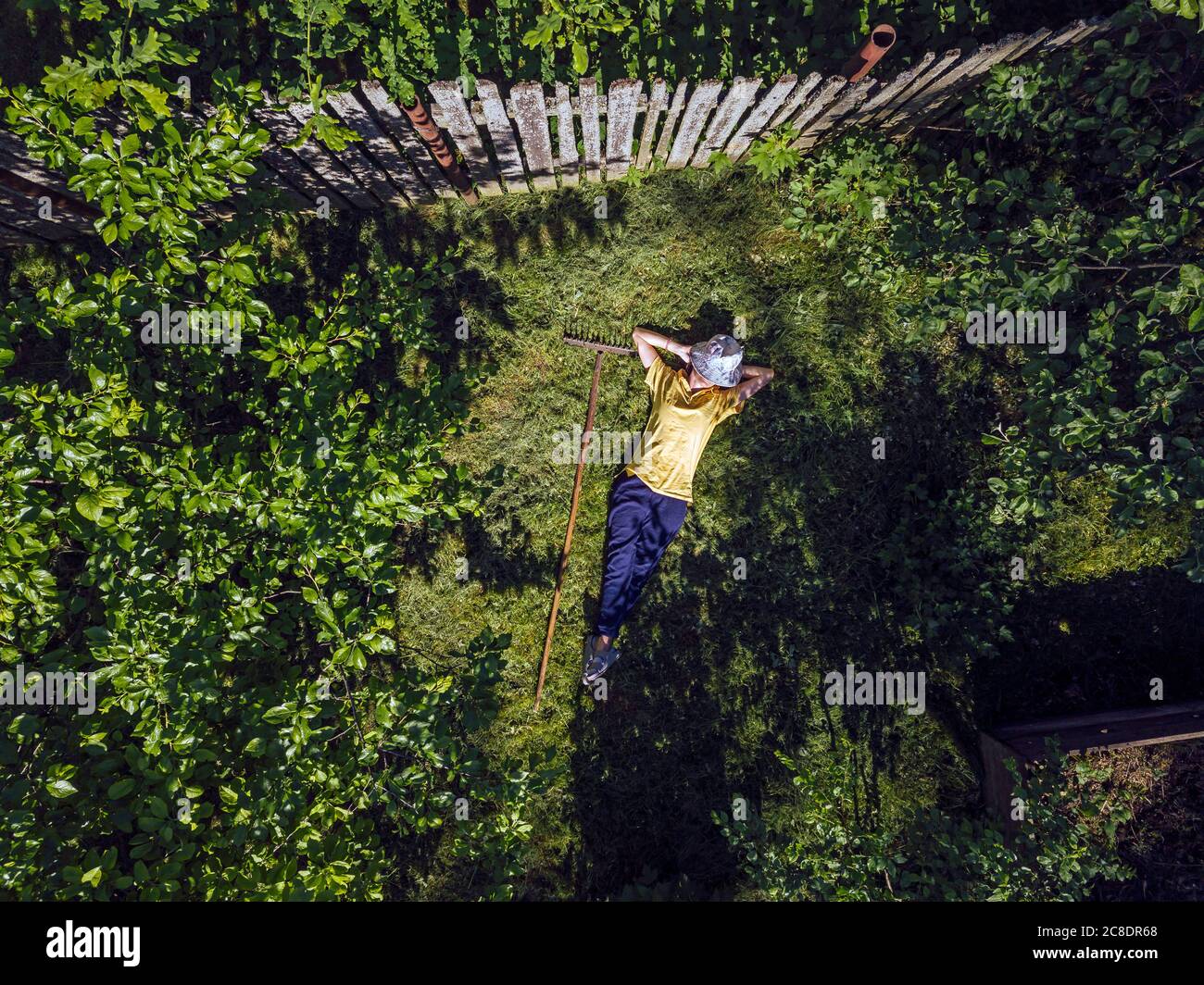 Vue aérienne d'une femme adulte de taille moyenne avec les mains derrière la tête repos sur terre herbeuse dans la cour Banque D'Images