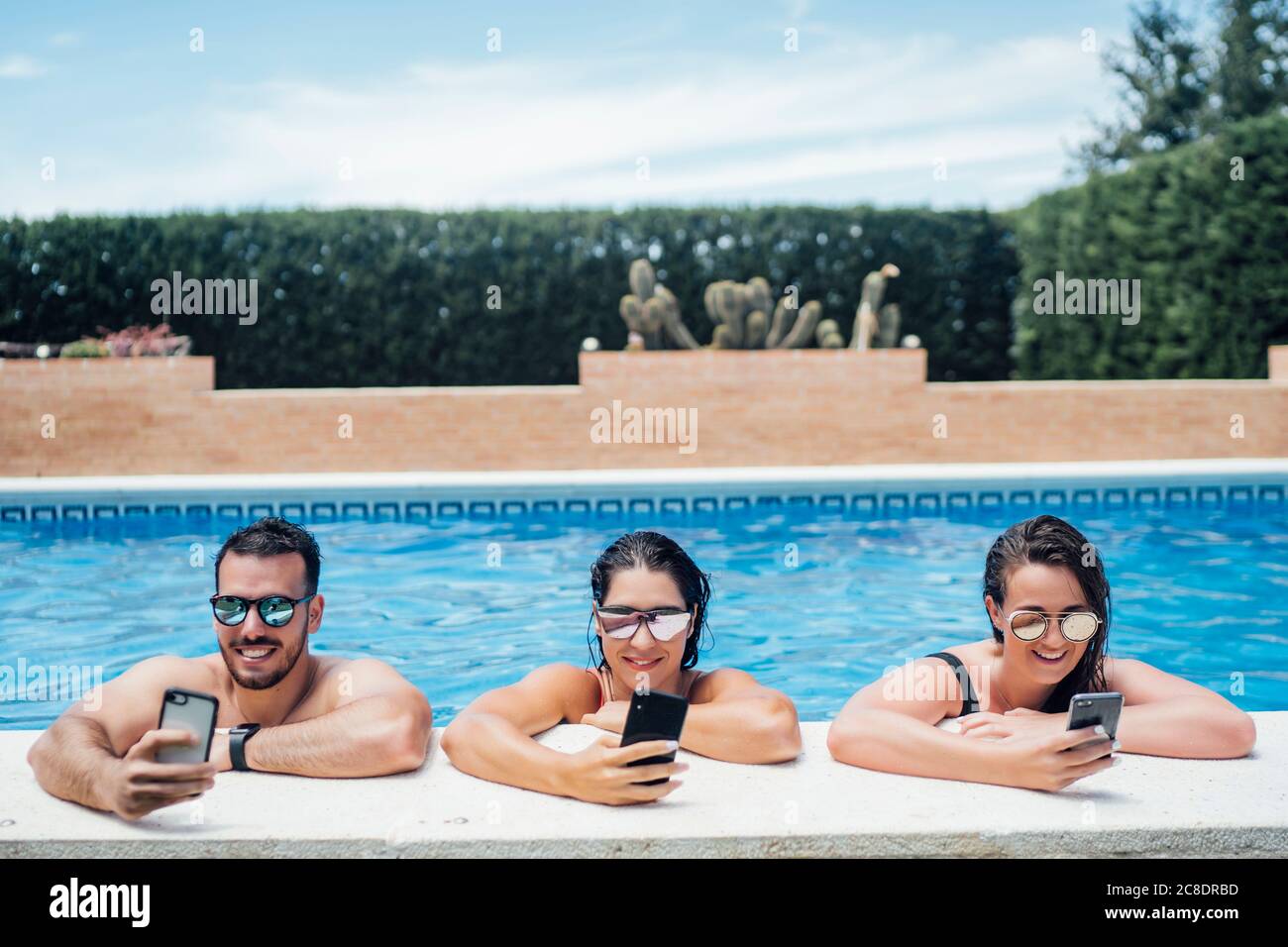 Amis pendant une fête en piscine avec un smartphone Banque D'Images