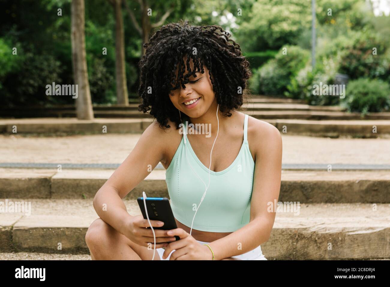 Jeune femme sportive utilisant un smartphone dans le parc Banque D'Images