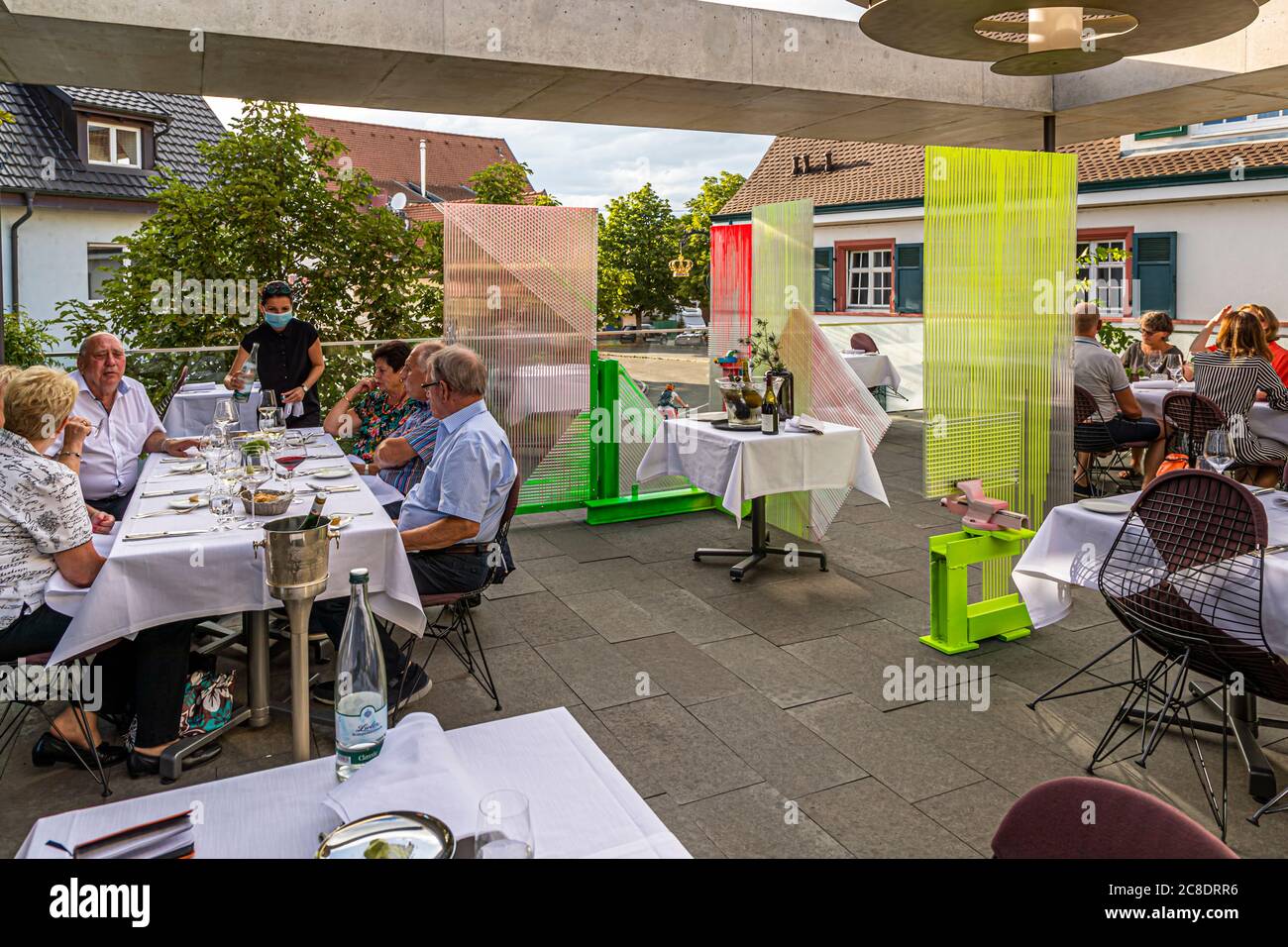Restauration extérieure avec cloisons artistiquement conçues et serveurs avec masques de protection à l'Hôtel Krone à Weil am Rhein, Allemagne Banque D'Images