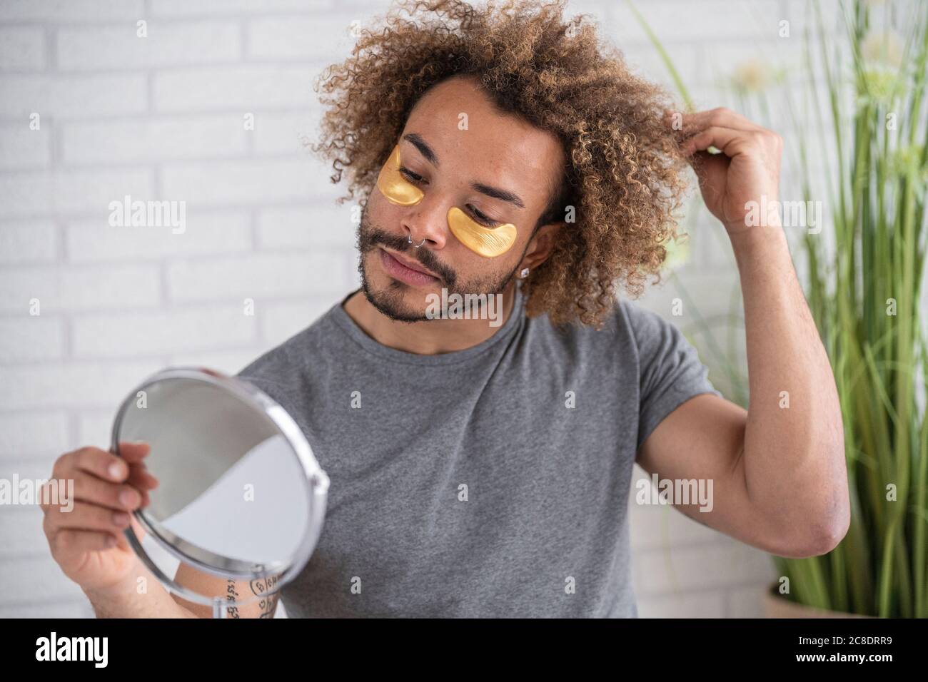 Gros plan d'un jeune homme avec des taches oculaires sur le visage dans le miroir à la maison Banque D'Images