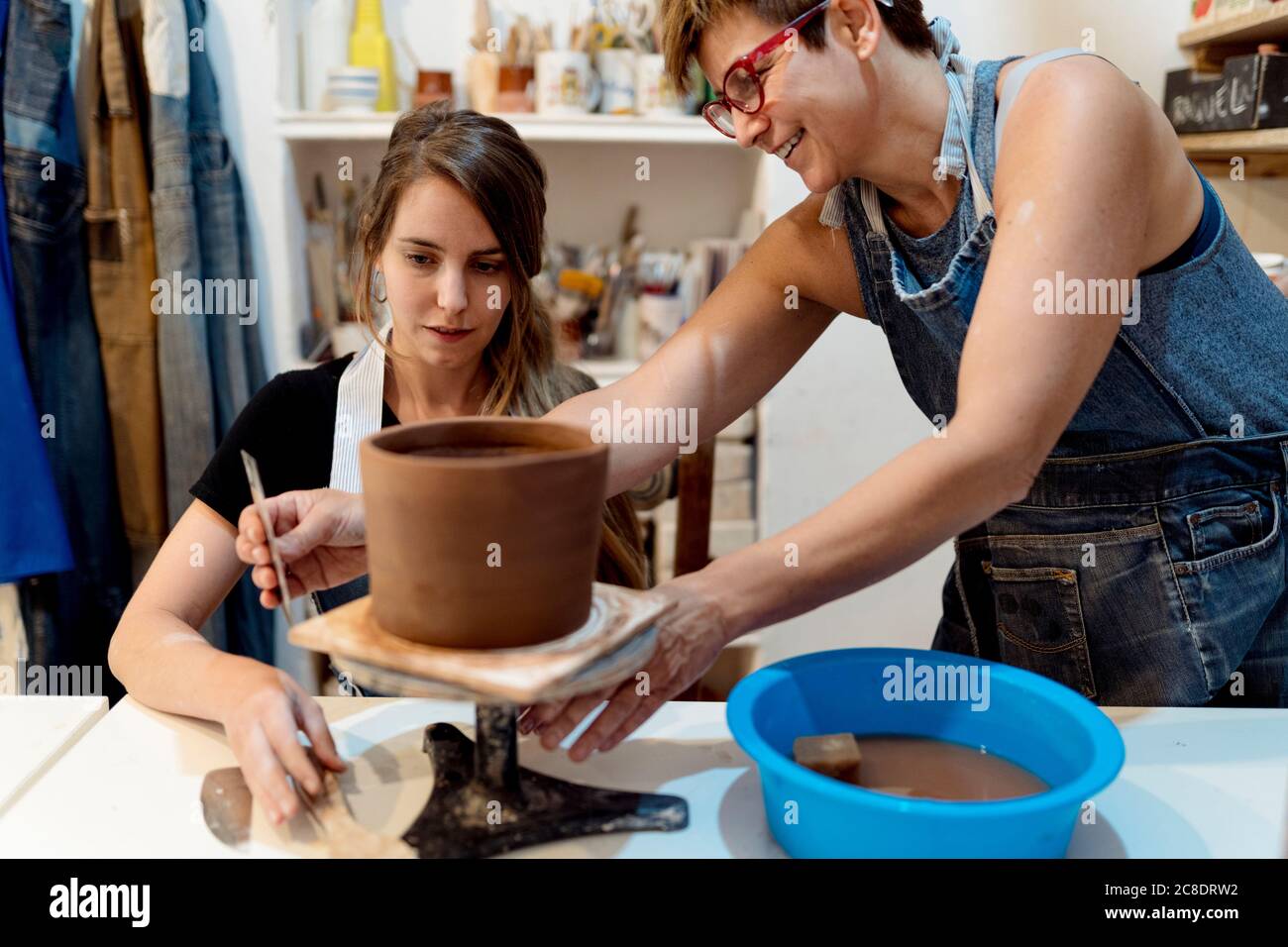 Femme mature enseignant la poterie à une collègue en studio Banque D'Images