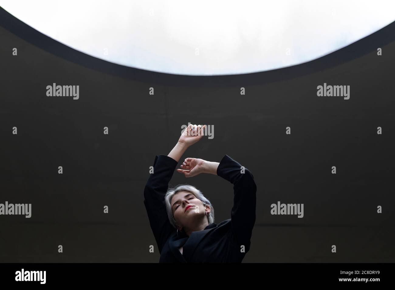 Élégante femme professionnelle vêtue d'une combinaison élégante contre une lumière éclairée au bureau Banque D'Images