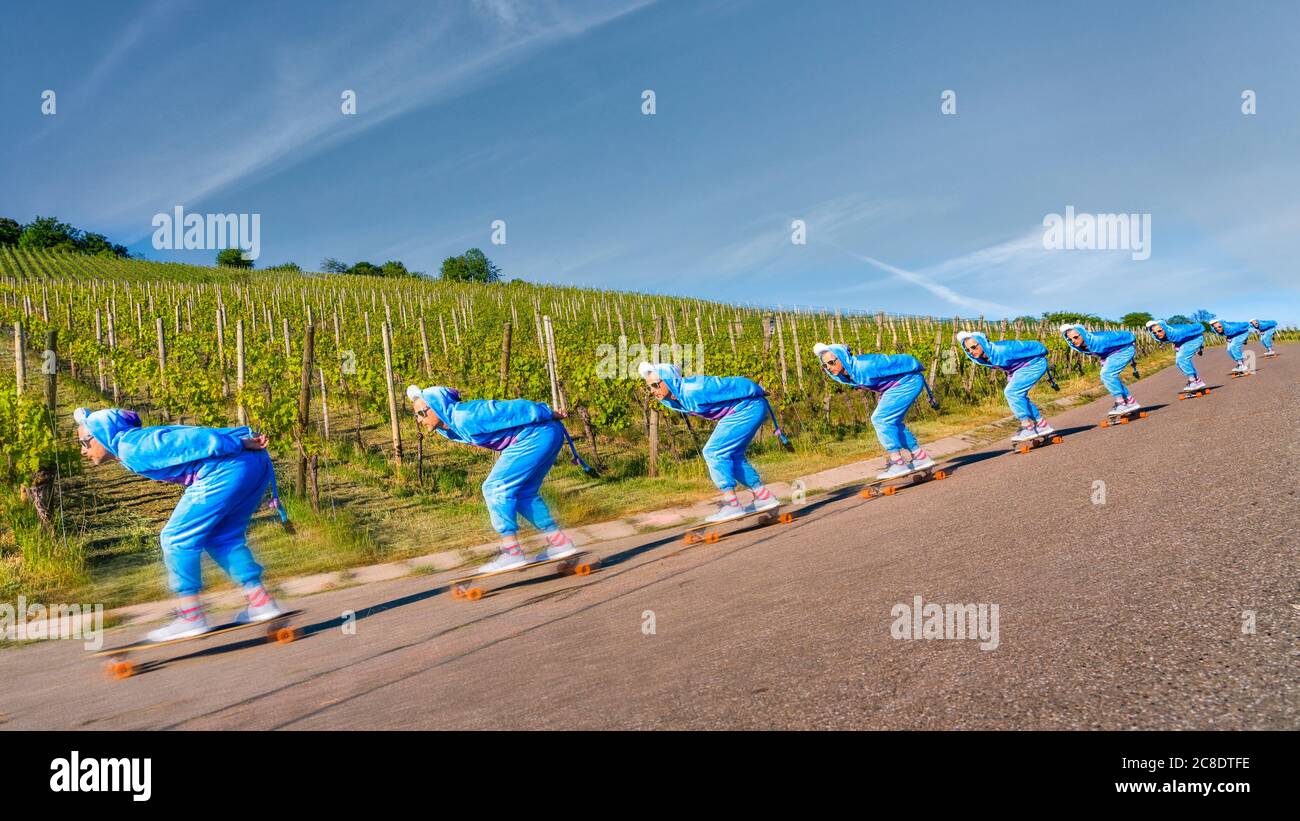 Homme mature en costume bleu skate sur la route en bord de vignoble contre le ciel pendant la journée ensoleillée Banque D'Images