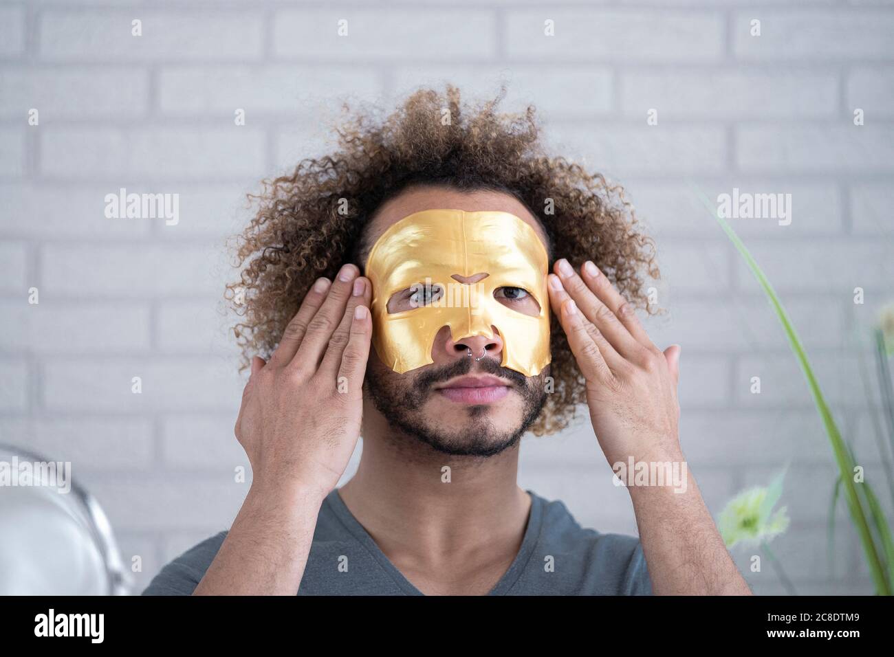 Gros plan d'un jeune homme appliquant un masque facial à la maison Banque D'Images