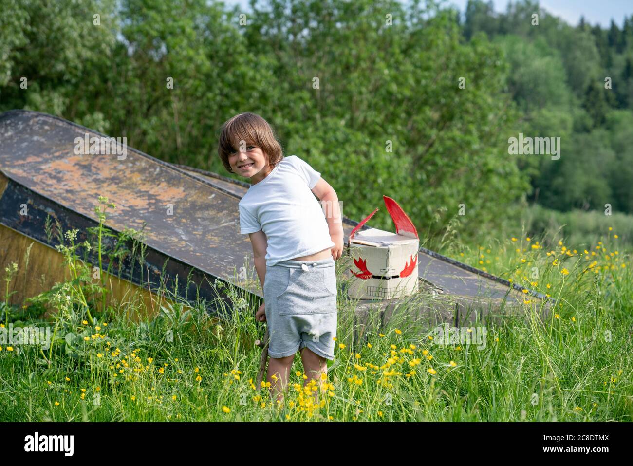 Garçon souriant avec masque sur le bateau abandonné debout au milieu des plantes en forêt Banque D'Images