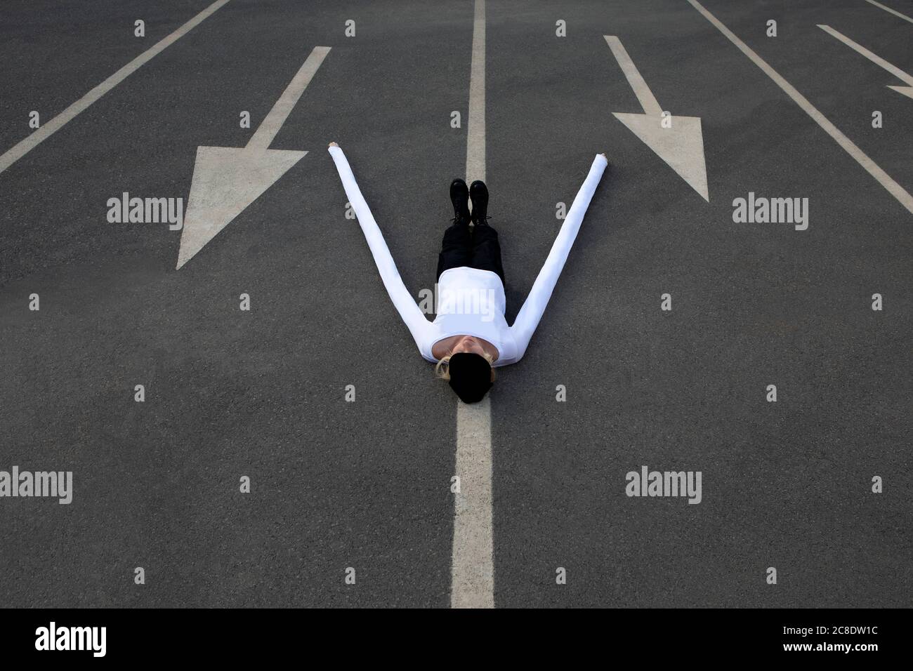 Femme avec de longues mains artificielles au milieu des symboles de flèche sur route Banque D'Images