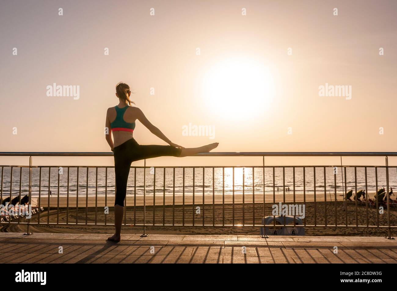 Femme sportive s'étendant sur le front de mer au lever du soleil, Gran Canaria, Espagne Banque D'Images