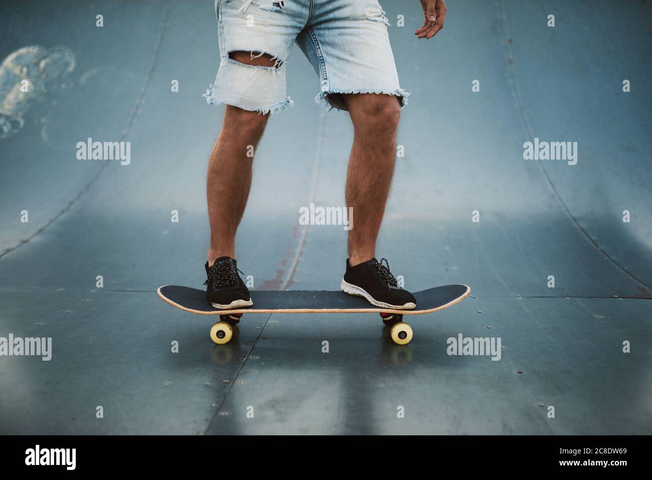 Jeune homme skateboarding sur rampe à sports park Banque D'Images