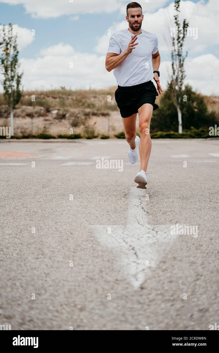 Athlète masculin en train de courir avec le signe de la flèche sur la route Banque D'Images