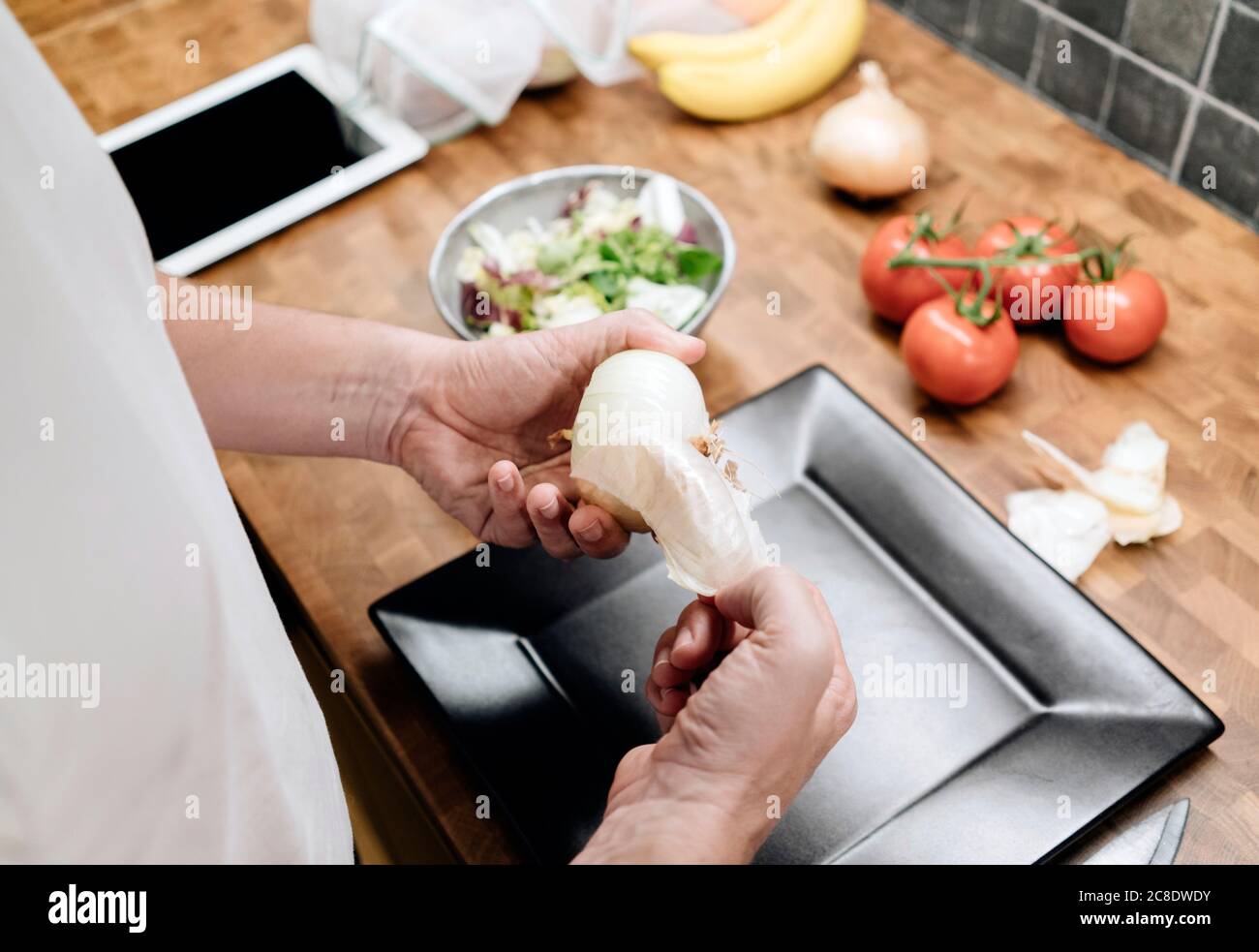 Homme mûr debout dans la cuisine, épluchant les oignons Banque D'Images