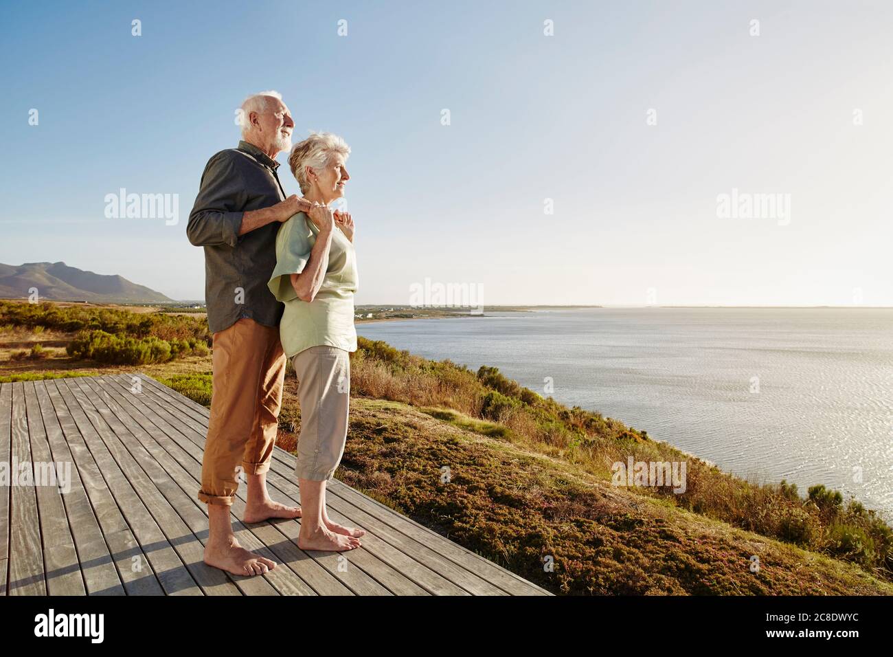 Couple senior offrant la vue sur la terrasse en bois du mer Banque D'Images