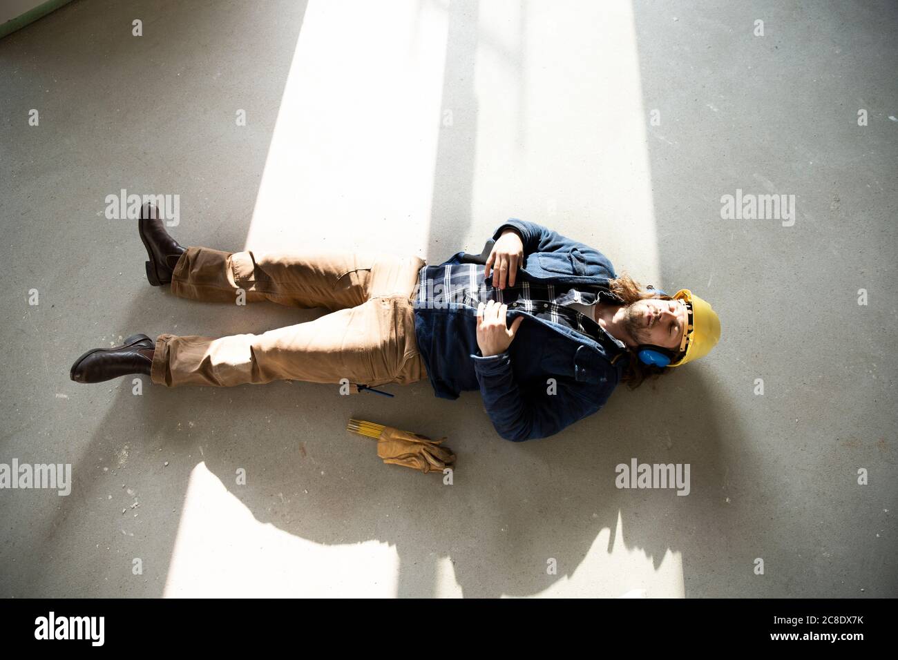 Travailleur de la construction dormant au sol dans la maison en rénovation Banque D'Images