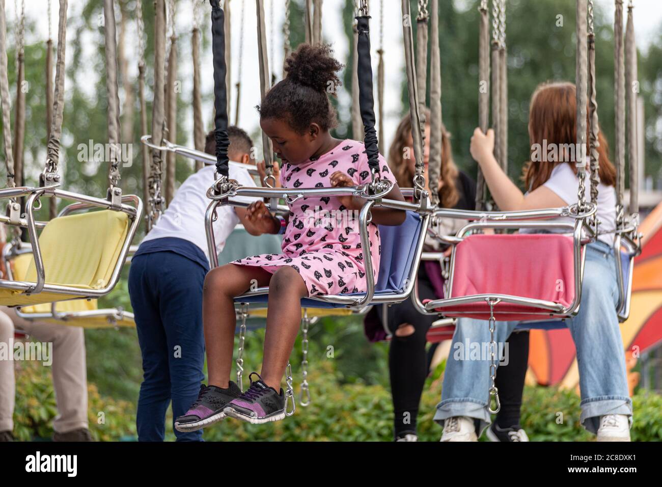 Jeune fille dans un carrousel de balançoire de chaise avant le trajet dans le parc d'attractions Linnanmäki, Helsinki, Finlande Banque D'Images