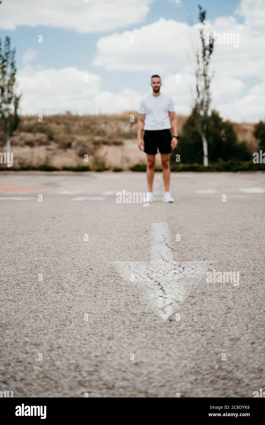 Athlète masculin debout au panneau fléché sur la route Banque D'Images