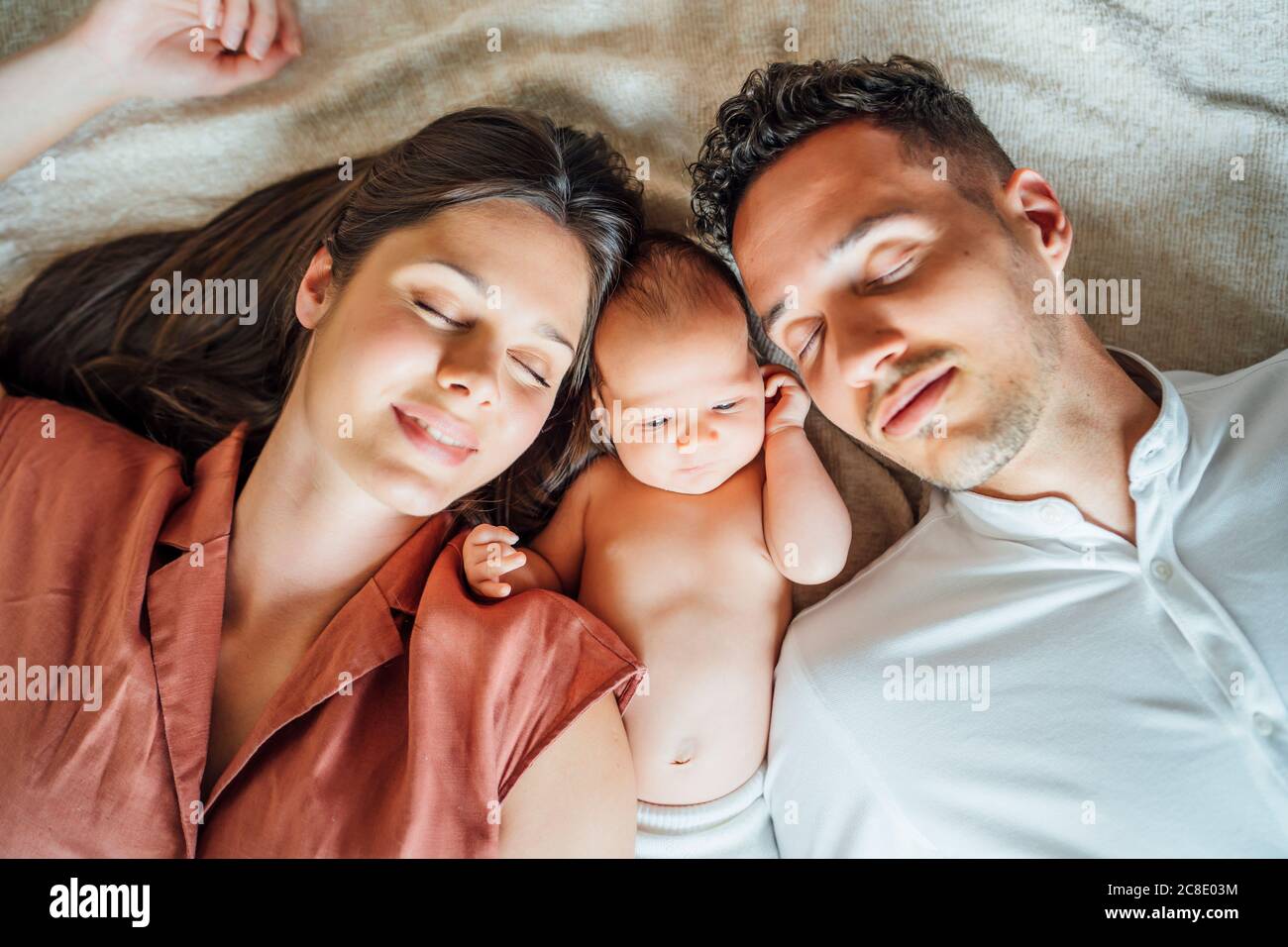 Parents dormant avec bébé garçon au lit à la maison Banque D'Images