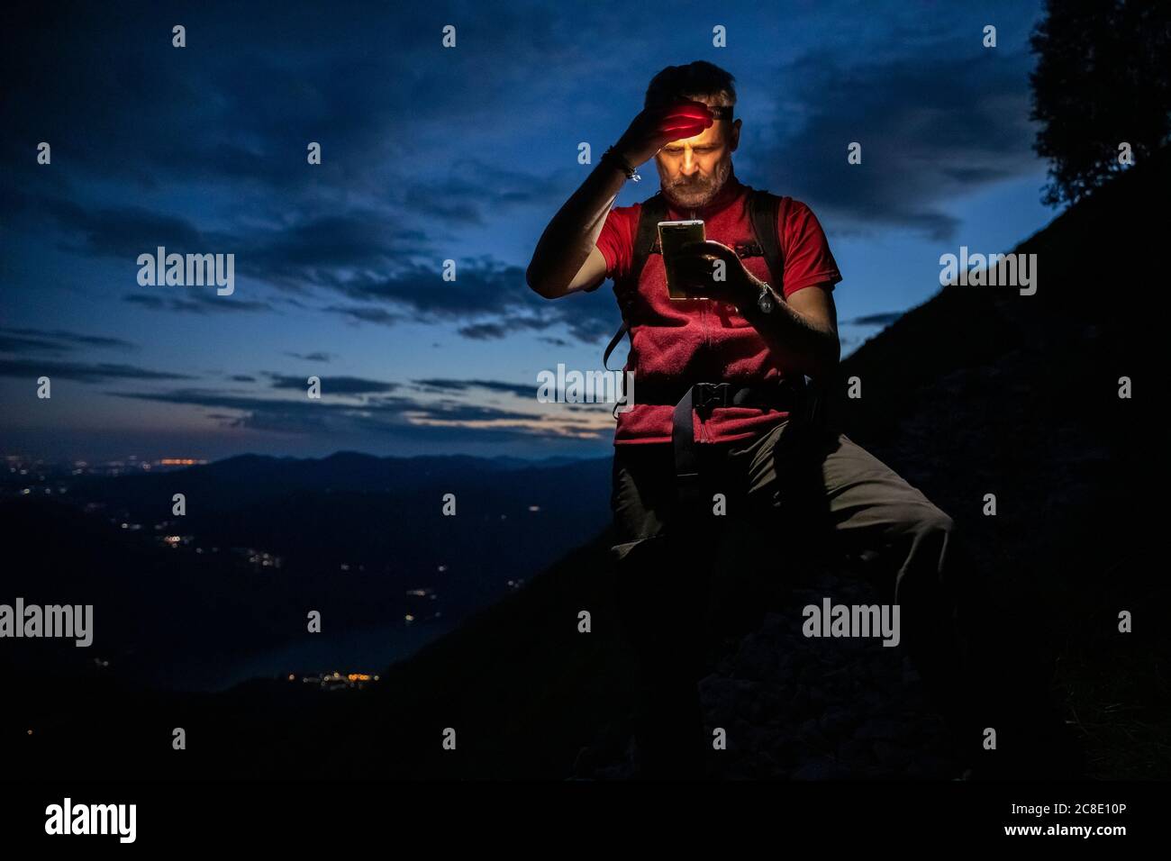 Homme randonneur qui vérifie la carte sur smartphone tout en étant debout en montagne la nuit, Orobie, Lecco, Italie Banque D'Images