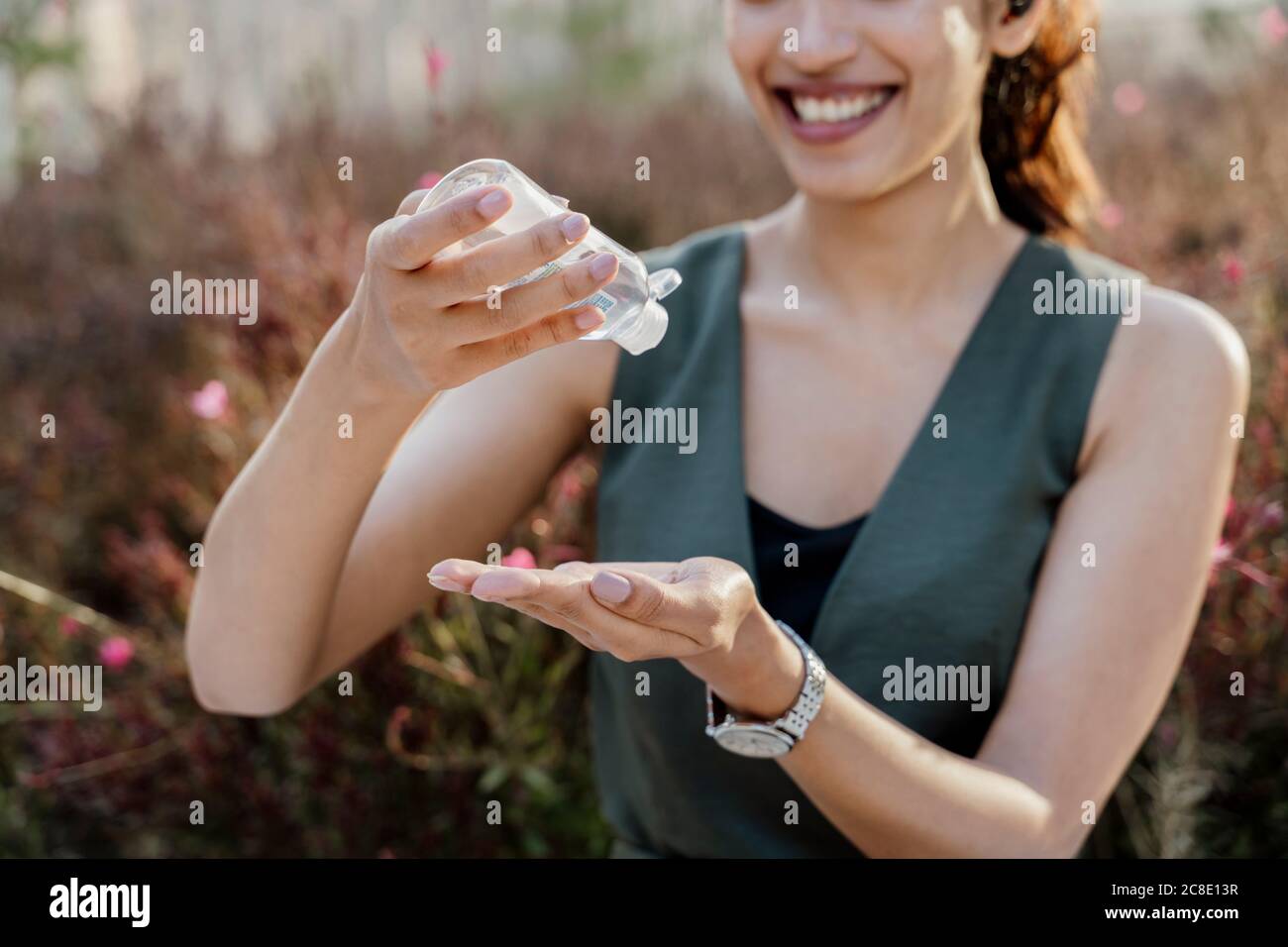 Gros plan d'une femme d'affaires souriante se lavant les mains avec de l'assainisseur en position debout à l'extérieur Banque D'Images