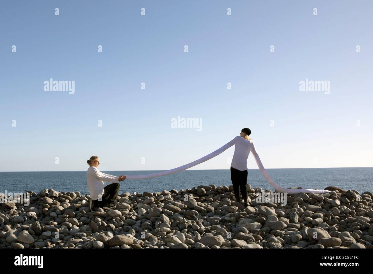 Homme mature proposant tout en tenant la longue main artificielle de la femme à plage contre ciel clair Banque D'Images