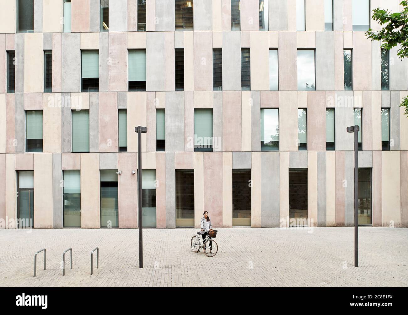 Femme d'affaires debout avec un vélo dans la rue à l'extérieur du bureau Banque D'Images