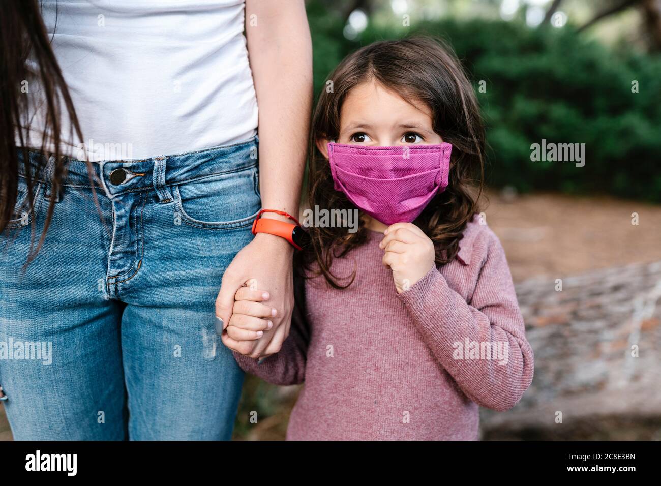 Fille portant un masque de protection et tenant la main de sa mère Banque D'Images