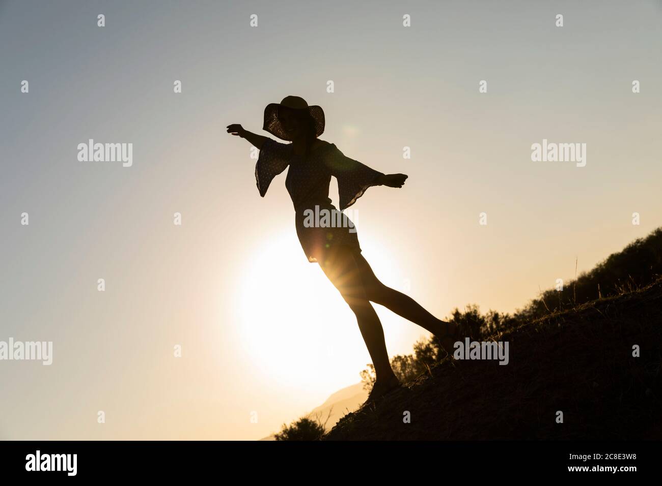 Jeune femme debout avec les bras s'étiré sur la colline contre ciel dégagé Banque D'Images