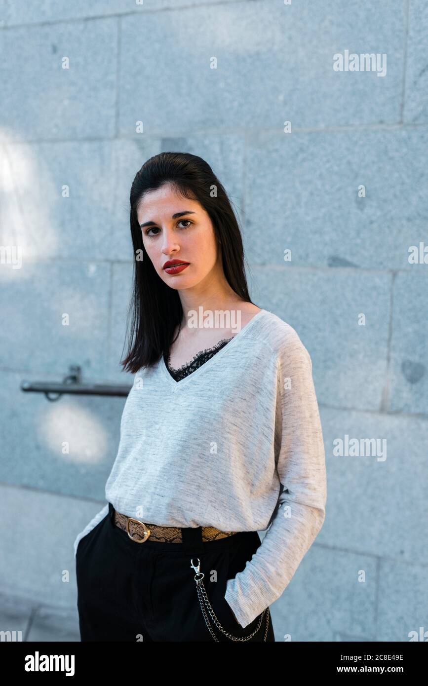 Belle femme avec les mains dans les poches debout contre le mur Banque D'Images