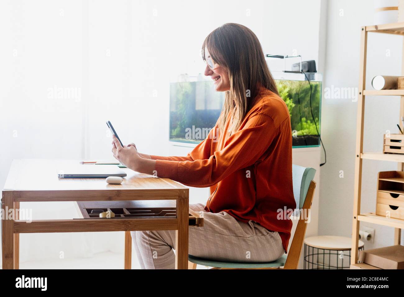 Femme indépendante travaillant à la maison assise au bureau à l'aide d'un smartphone Banque D'Images