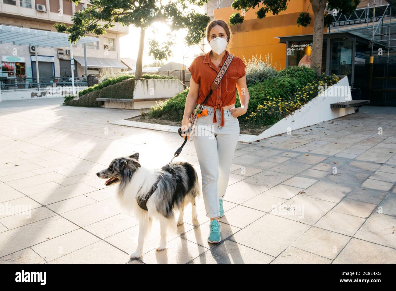 Jeune femme portant un masque de protection allant des walkies avec son chien dans la ville Banque D'Images