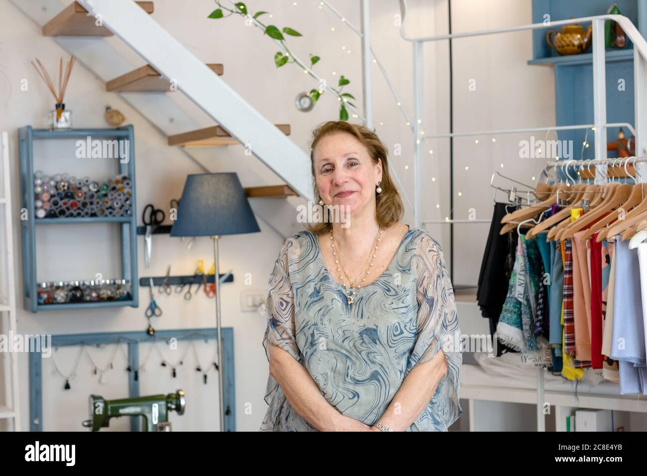 Une femme de conception professionnelle souriante se tient dans un studio de mode éclairé Banque D'Images