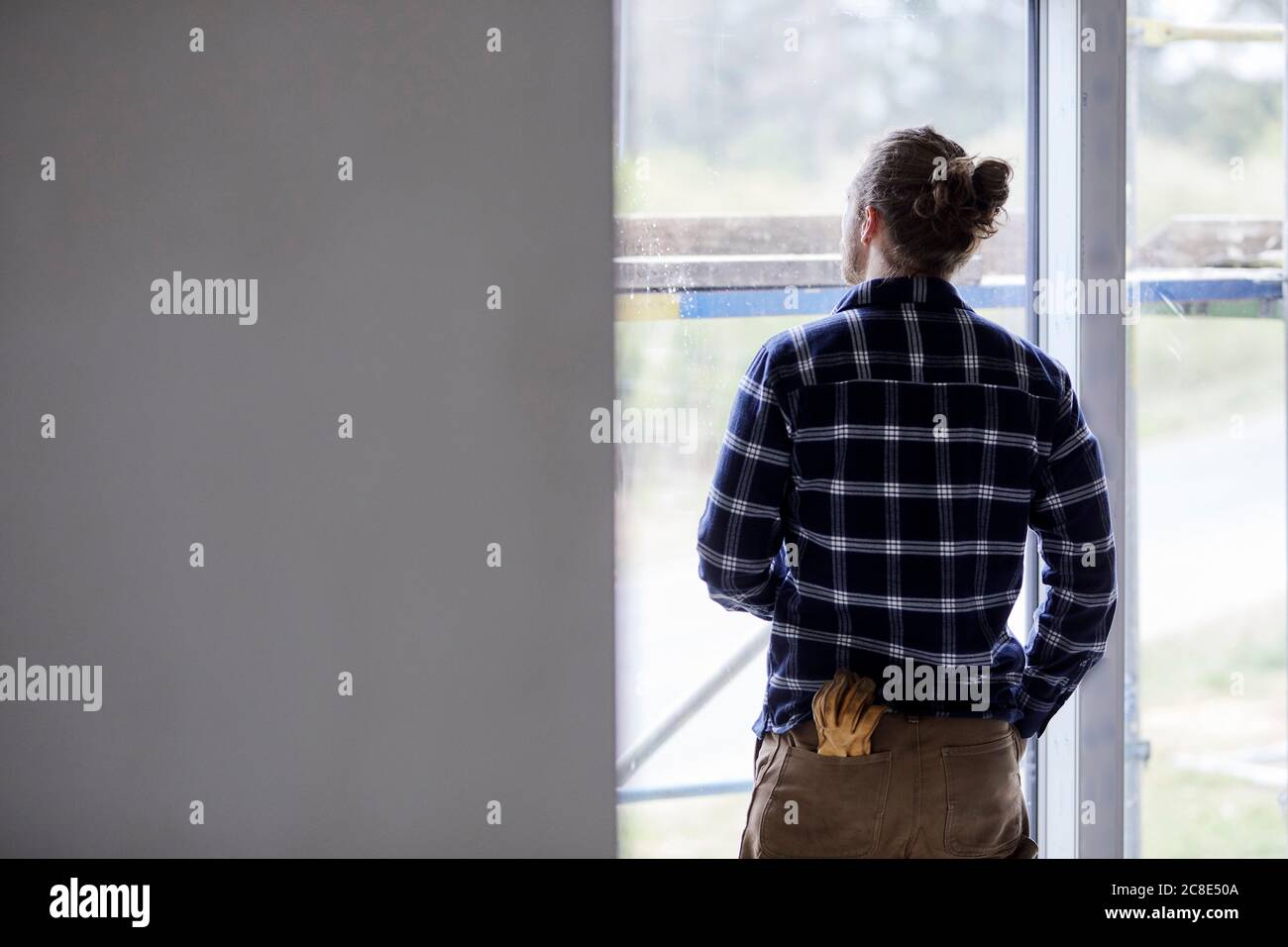 Employé sur un chantier de construction, regardant par la fenêtre Banque D'Images