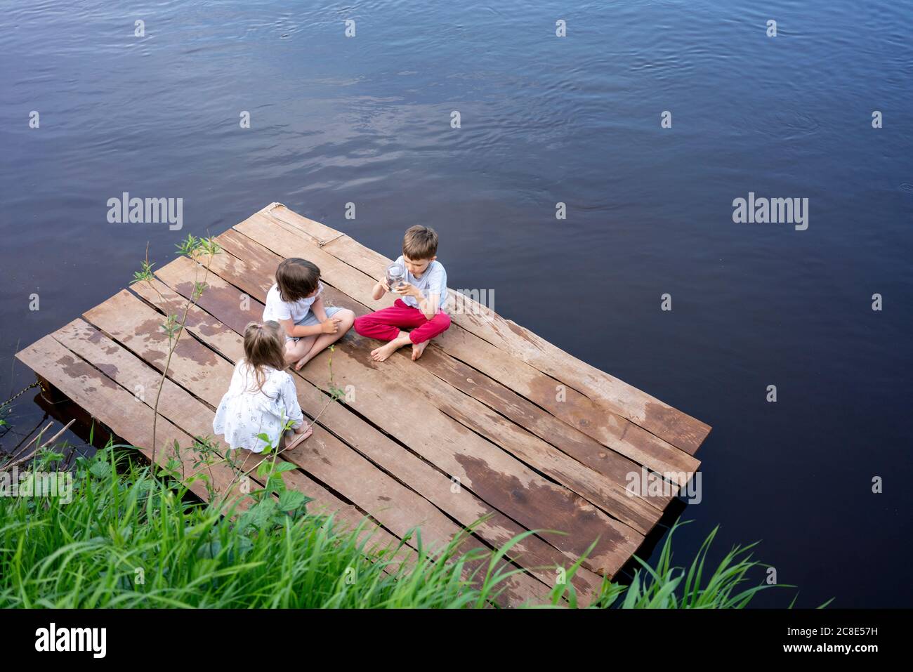 Enfants jouant sur la jetée au-dessus du lac en forêt Banque D'Images